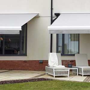 Eastbourne Shutters & Awnings - a photo of two white awnings extended from the back of a home over a patio