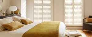 Slide-3 a bedroom, white and mustard yellow decor with full height white shutters fitted