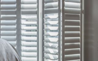 shutters in east sussex - an image of white door shutters, one is slightly bent as though the shutter is partially opened