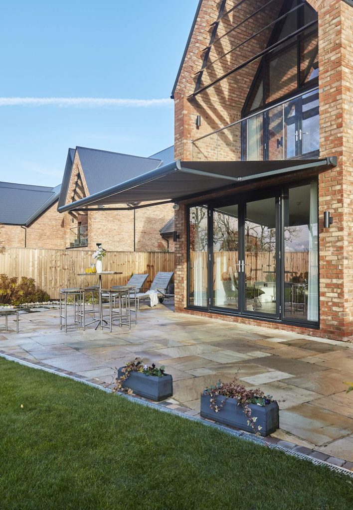 awning styles - an awning extended over a large glass rear door of a modern brick home.