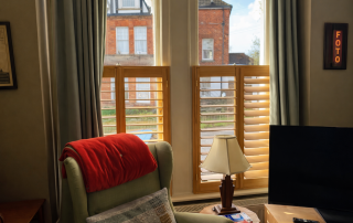 natural wood cafe style shutters in a reading room or study perhaps with a safe green armchair and small lamp